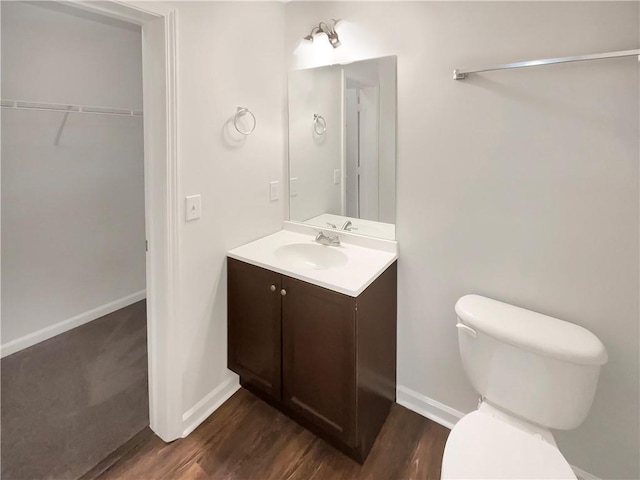 bathroom with vanity, toilet, wood finished floors, and baseboards