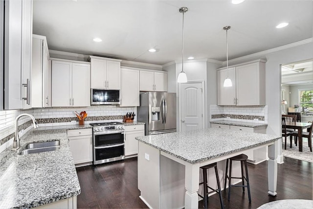 5696 Walnut Mill Ln, Powder Springs, GA 30127 - kitchen featuring appliances with stainless steel finishes, crown molding, decorative backsplash, light stone countertops, and a kitchen bar