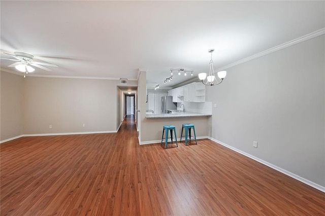 kitchen featuring stainless steel refrigerator, dark hardwood / wood-style floors, ornamental molding, white cabinets, and kitchen peninsula