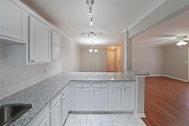 kitchen with crown molding, decorative light fixtures, kitchen peninsula, and white cabinets