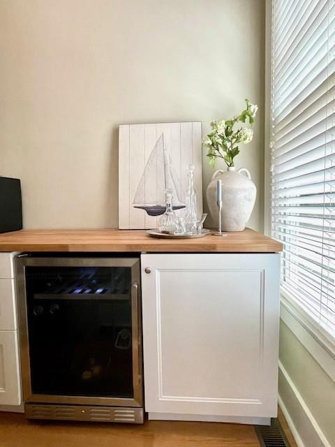 bar with wine cooler and light wood finished floors