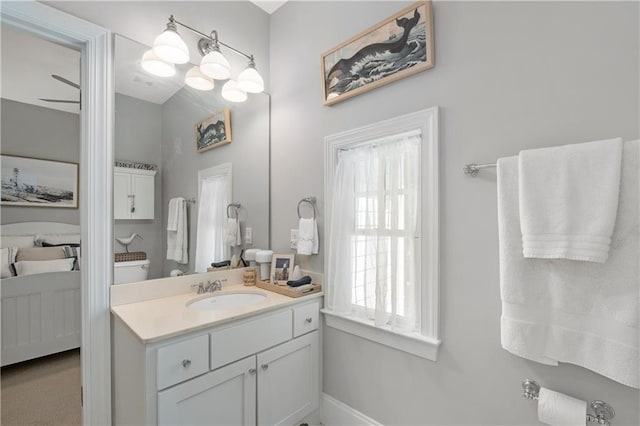 ensuite bathroom featuring vanity, connected bathroom, and baseboards