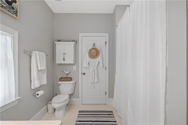 full bathroom featuring plenty of natural light, baseboards, tile patterned floors, and toilet