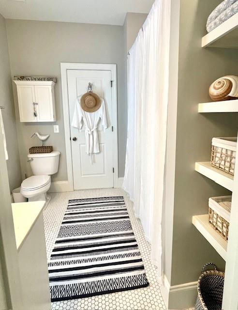 bathroom featuring toilet, tile patterned floors, and baseboards