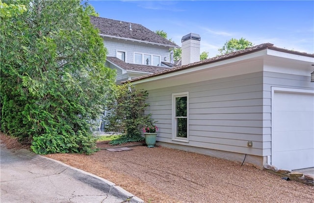view of side of home featuring a chimney and a garage
