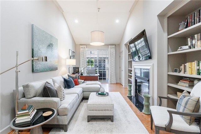 living room featuring lofted ceiling, a chandelier, ornamental molding, light hardwood / wood-style floors, and decorative columns