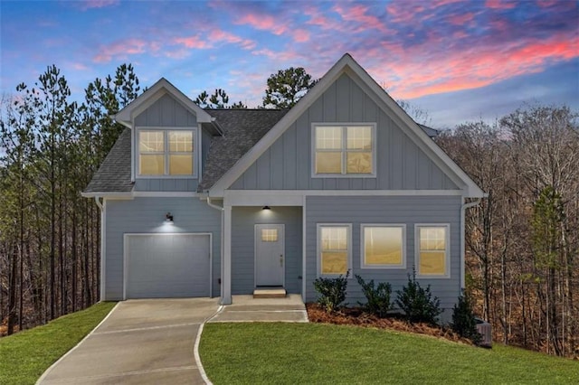 view of front of home featuring a lawn, concrete driveway, board and batten siding, and roof with shingles