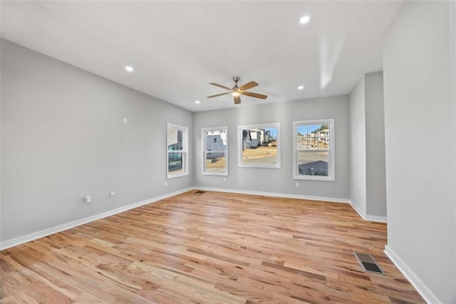 empty room with a wealth of natural light, light wood finished floors, visible vents, and recessed lighting