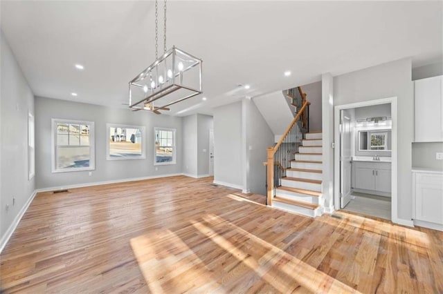 unfurnished living room with stairs, recessed lighting, baseboards, and light wood-style floors