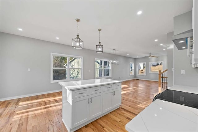 kitchen featuring recessed lighting, open floor plan, light countertops, light wood finished floors, and pendant lighting