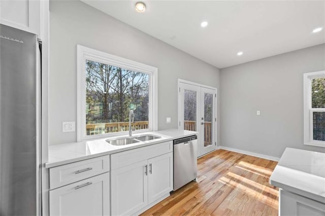 kitchen with appliances with stainless steel finishes, white cabinets, a healthy amount of sunlight, and a sink