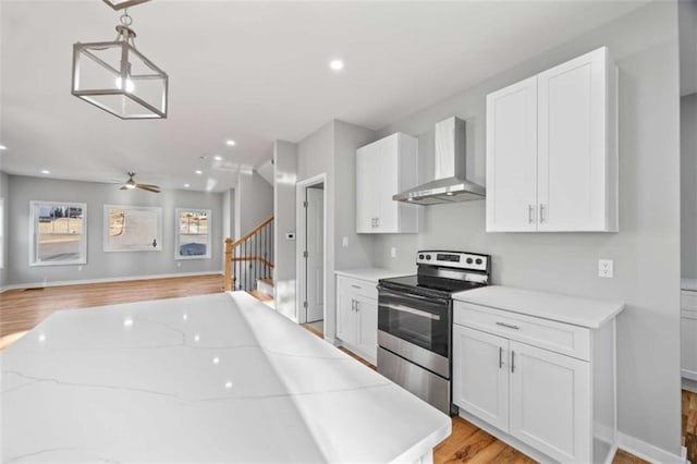 kitchen featuring light countertops, electric range, and wall chimney exhaust hood