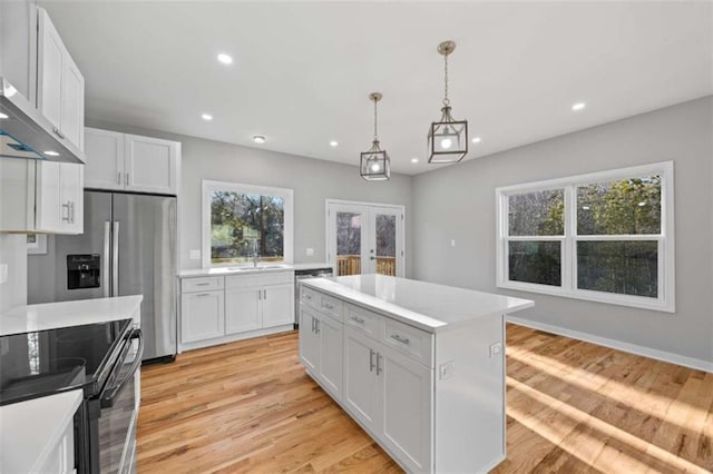 kitchen with recessed lighting, french doors, light countertops, and wall chimney exhaust hood