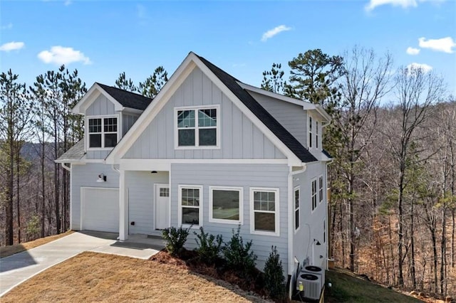 view of front of home featuring a garage, central AC, a shingled roof, concrete driveway, and board and batten siding