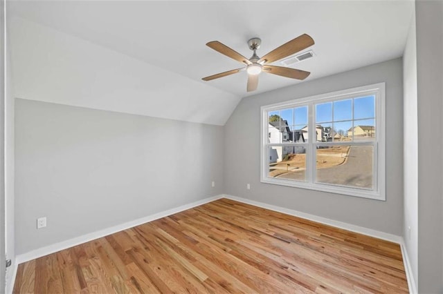 additional living space featuring baseboards, visible vents, a ceiling fan, wood finished floors, and vaulted ceiling