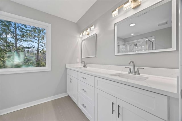 bathroom with double vanity, walk in shower, a sink, and baseboards