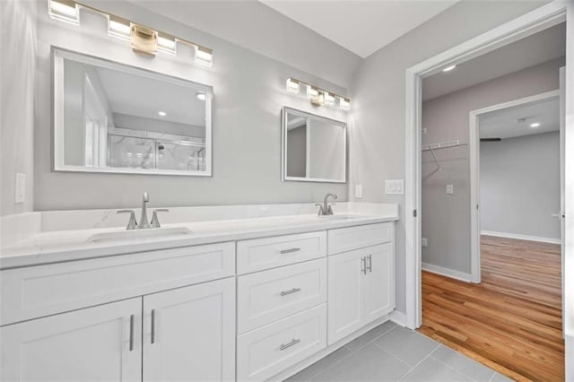 full bathroom featuring double vanity, a sink, and baseboards