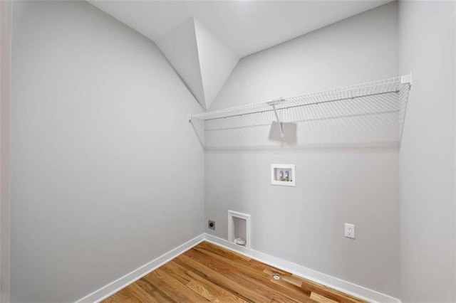 clothes washing area featuring hookup for a washing machine, hookup for an electric dryer, wood finished floors, laundry area, and baseboards