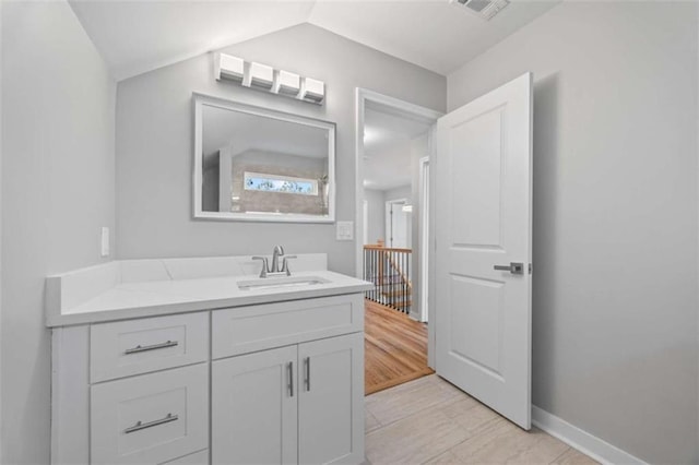 bathroom with lofted ceiling, visible vents, baseboards, and vanity