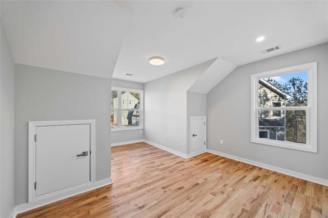 bonus room featuring light wood-type flooring, baseboards, visible vents, and vaulted ceiling