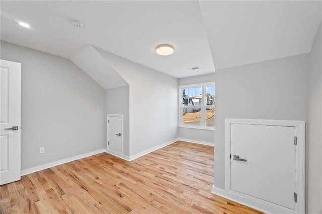 bonus room with light wood-style flooring, visible vents, baseboards, and vaulted ceiling