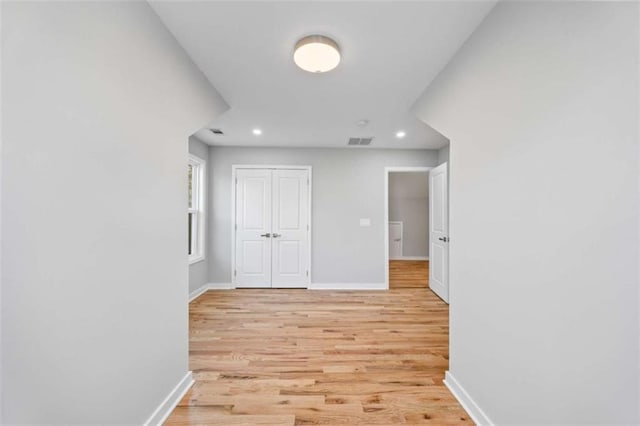 corridor with light wood-style flooring, recessed lighting, visible vents, and baseboards