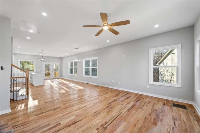 unfurnished living room with light wood-type flooring, visible vents, and baseboards