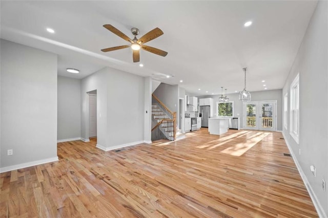 unfurnished living room with light wood-style floors, baseboards, stairway, and recessed lighting