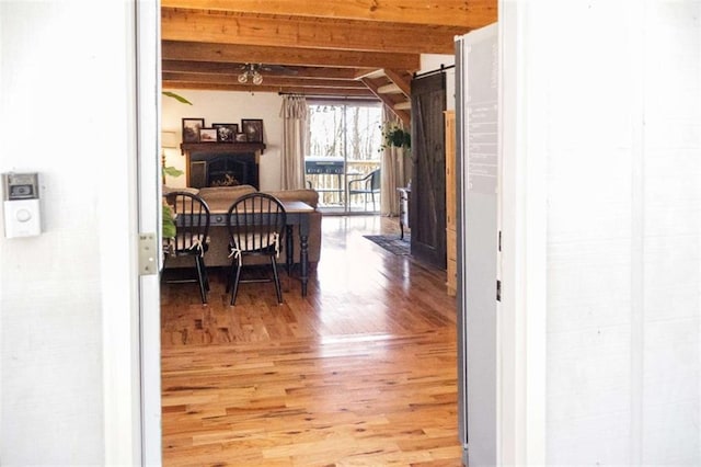 hallway featuring a barn door, light wood-style flooring, and beam ceiling