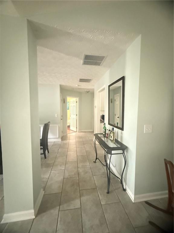 3484 Lynley Mill Ln, Dacula, GA 30019 - corridor with a textured ceiling, baseboards, and light tile patterned floors