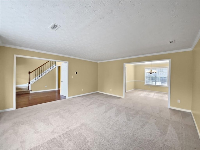 carpeted empty room featuring crown molding, a notable chandelier, visible vents, baseboards, and stairs