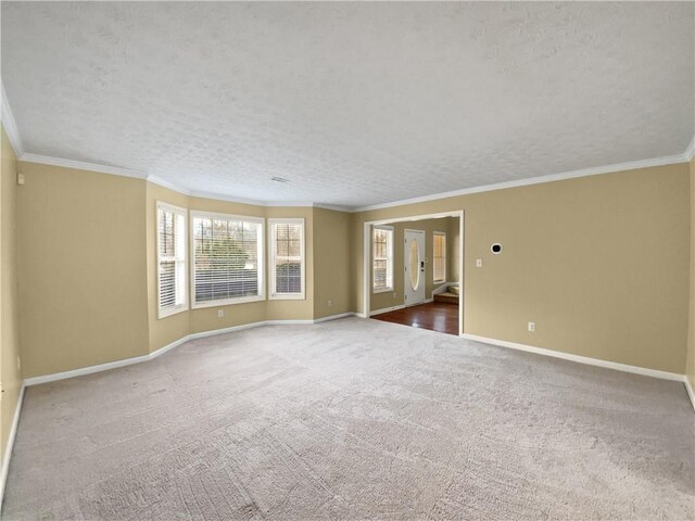 carpeted empty room with baseboards, a textured ceiling, and ornamental molding