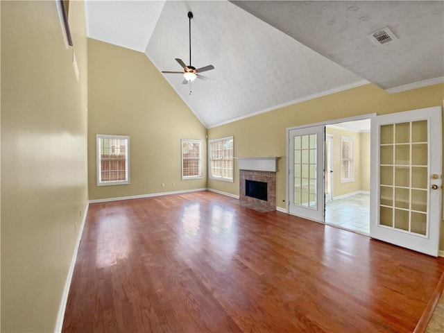 unfurnished living room featuring visible vents, a tiled fireplace, ceiling fan, wood finished floors, and baseboards