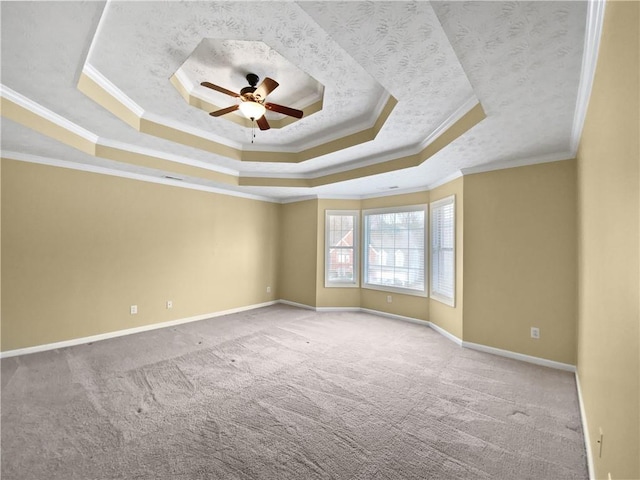 carpeted spare room featuring baseboards, crown molding, a tray ceiling, and a ceiling fan