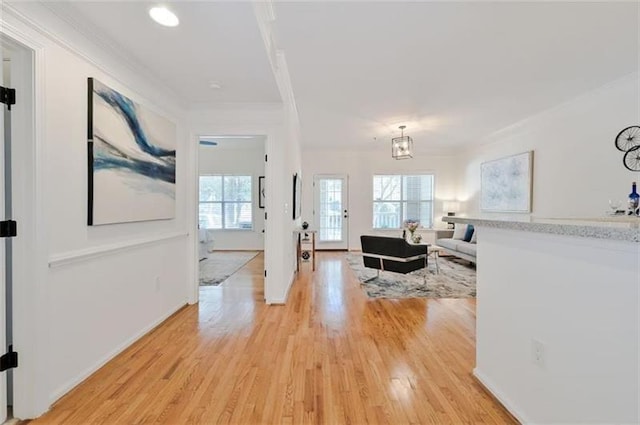 living room featuring light wood-type flooring, ornamental molding, and an inviting chandelier