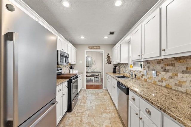 kitchen with visible vents, backsplash, appliances with stainless steel finishes, white cabinets, and a sink