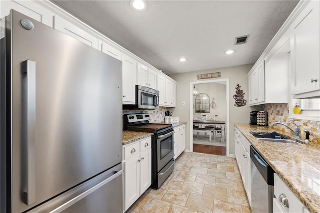 kitchen featuring tasteful backsplash, visible vents, appliances with stainless steel finishes, white cabinetry, and a sink