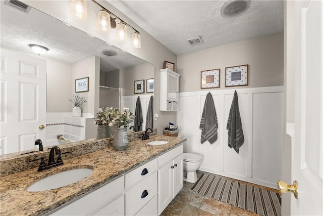 full bathroom with a sink, visible vents, toilet, and wainscoting