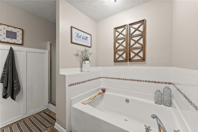 full bath with a garden tub, a wainscoted wall, a shower stall, and a textured ceiling