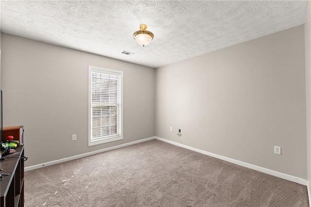 carpeted spare room featuring baseboards, visible vents, and a textured ceiling