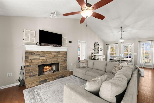 living room with visible vents, baseboards, a stone fireplace, dark wood-type flooring, and vaulted ceiling