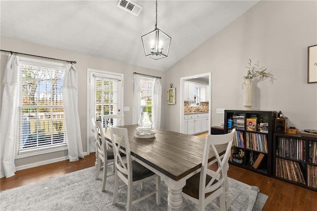 dining area with wood finished floors, baseboards, visible vents, lofted ceiling, and a chandelier