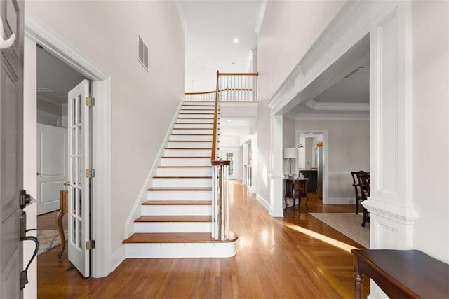 stairs featuring recessed lighting, wood finished floors, visible vents, baseboards, and ornamental molding