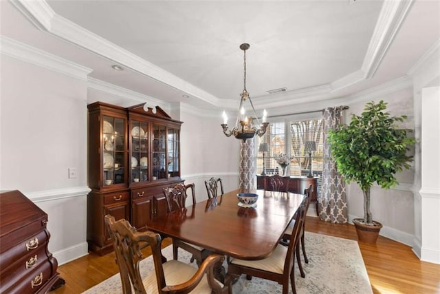 dining space featuring a raised ceiling, crown molding, and wood finished floors