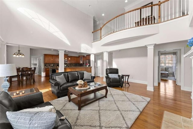 living area with baseboards, decorative columns, and light wood-style floors