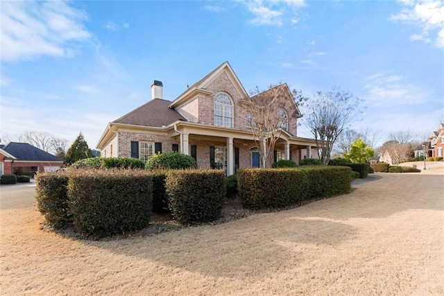 view of front of home featuring a chimney and brick siding