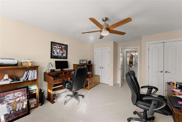 carpeted office space with a ceiling fan and baseboards