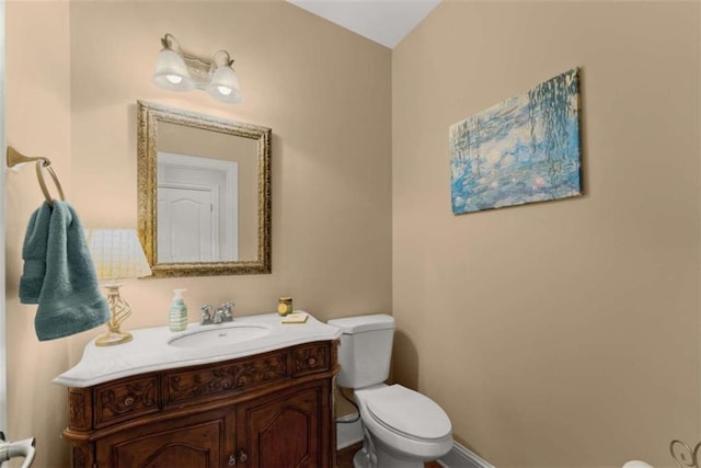 half bath with vanity, toilet, and baseboards