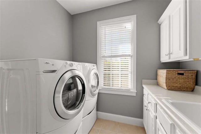 laundry room with washing machine and dryer, cabinet space, baseboards, and light tile patterned floors