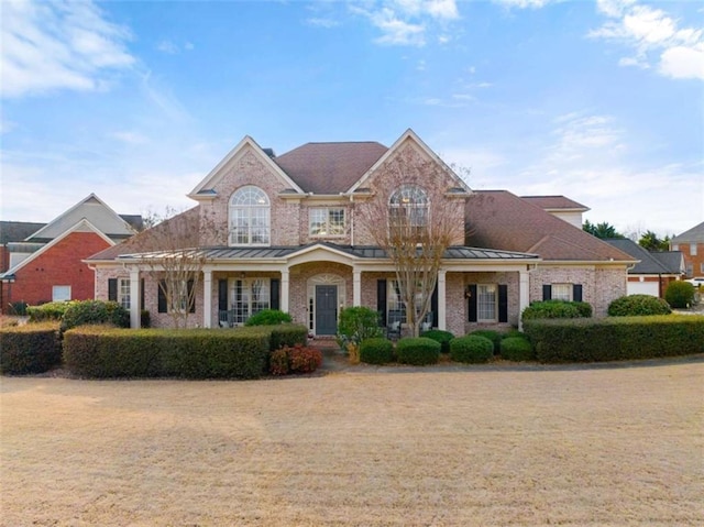 view of front of house featuring metal roof, brick siding, and a standing seam roof